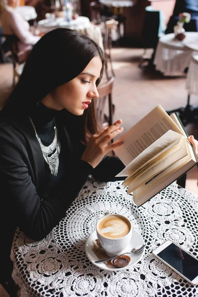 Portrait d'une belle fille lisant un livre dans un café. boisson — Photo