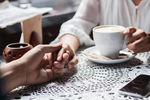 Jeune couple tenant la main au café, gros plan — Photo