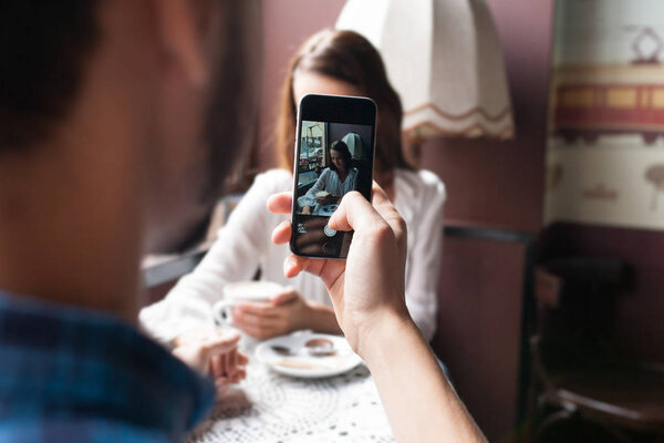 man photographs the girl in the cafe. love and technology