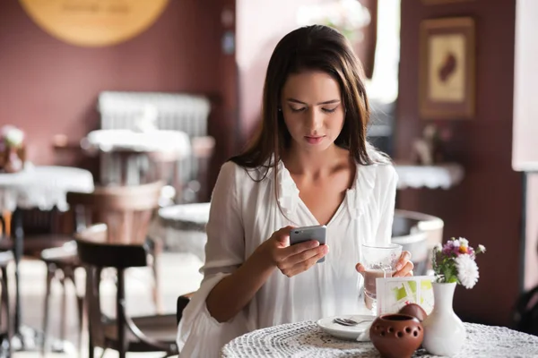 Image of young female reading sms on the phone in cafe — Stock Photo, Image
