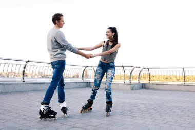 Güzel tatlı çift üzerinde paten el ele tutuşarak sürme