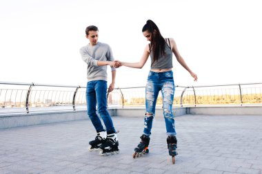 Güzel tatlı çift üzerinde paten el ele tutuşarak sürme