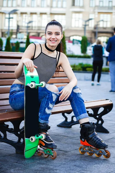 Válečkové dívka, která nosí džíny sedí na lavičce venku — Stock fotografie