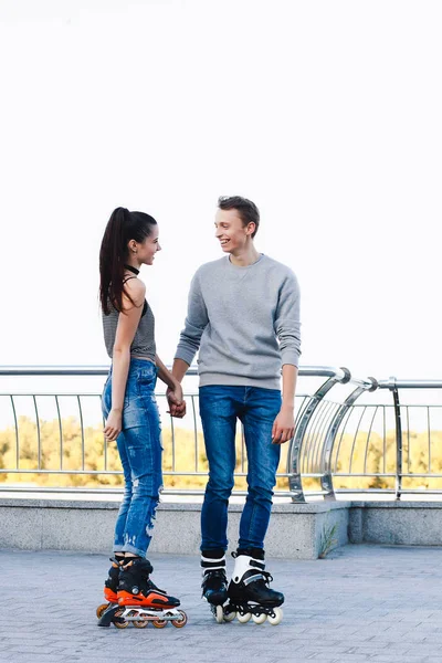 Beautiful sweet couple riding on roller skates holding hands