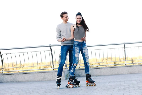 Beau couple doux chevauchant sur des patins à roulettes tenant la main — Photo