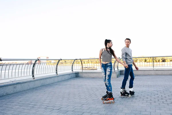 Beautiful sweet couple riding on roller skates holding hands