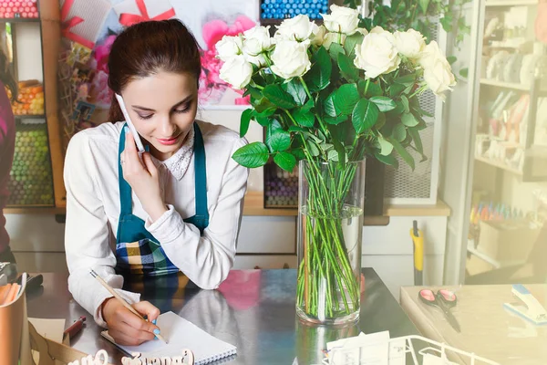 Potret penjual bunga tersenyum berdiri di dekat meja dengan bunga-bunga — Stok Foto