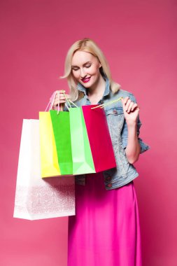 Alışveriş alışveriş torbaları, pembe arka plan tutan kadın