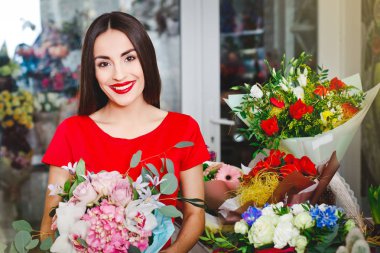 Kırmızı elbiseli esmer güzel bir buket çiçek çiçekçi dükkanı satın alır.