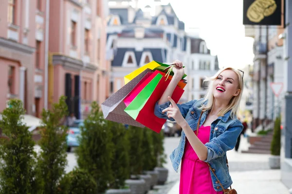 買い物袋を持つ少女の笑みを浮かべてください。市内の街を歩く — ストック写真