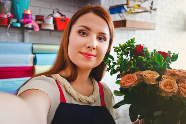 Chica joven que trabaja en una floristería, Floristería hace foto selfie con un ramo de flores —  Fotos de Stock