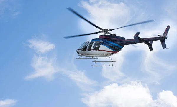 Helicopter flying through a blue sky with clouds — Stock Photo, Image
