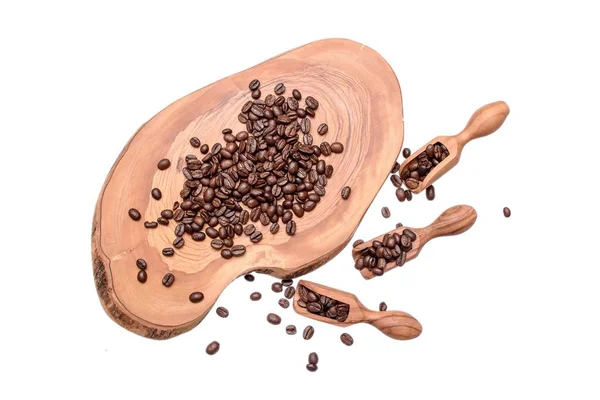Los granos de café enteros fritos se encuentran en una rebanada de un olivo, los granos de café se encuentran en una cucharada de árbol olift, aislados sobre un fondo blanco — Foto de Stock