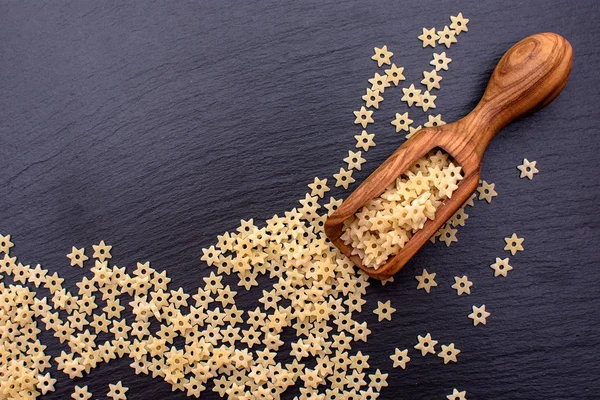 makarna yıldız şeklinde yalan bir tahta kaşık bir tahtada siyah taş, metin için yer içinde