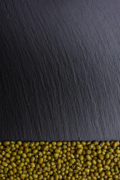 Mungbohnen liegen auf schwarzem Steintafelhintergrund, Platz für Text, Bohnen — Stockfoto