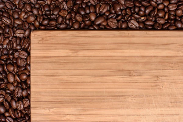 Um fundo de madeira ao redor das bordas polvilhado com café de grão torrado, espaço para texto — Fotografia de Stock