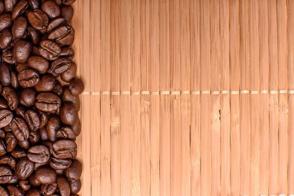 Fundo da esteira de bambu polvilhado ao redor das bordas de grãos fritos café, espaço para texto — Fotografia de Stock