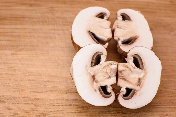 Gray mushrooms champignons lie on a wooden kitchen board Stock Image