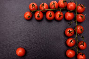 Kırmızı kiraz domates bir siyah taş kayrak kurulu, arka plan yalan