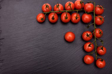 Kırmızı kiraz domates bir siyah taş kayrak kurulu, arka plan yalan