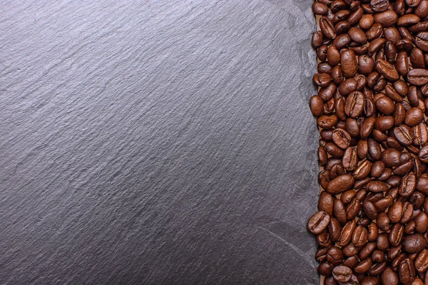 Stony black board sprinkled with nearby grain roasted coffee, place for tex, background and texture — Stock Photo, Image