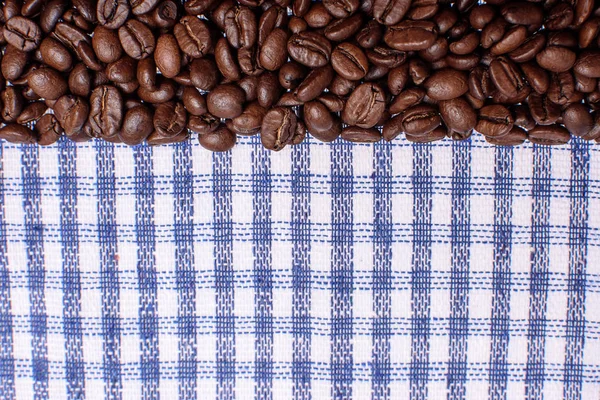 Textura de una toalla de color, una toalla de tipo celular, en la que se encuentra una cierta cantidad de granos de café marrón. Vista superior con un montón de granos de café con espacio para el texto — Foto de Stock