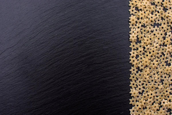 Makarna yıldız şeklinde bir taş yönetim kurulu, metin için yer siyah bir arka plan dayanmaktadır