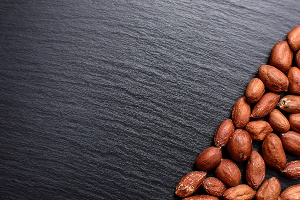 Kavrulmuş fıstık bir tahtada siyah taş, metin için yer soyulmuş