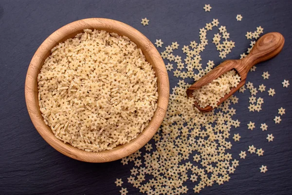 makarna starlets şeklinde yalan ahşap Kupası ve siyah bir taş masa, metin için yer bir ahşap Kepçe