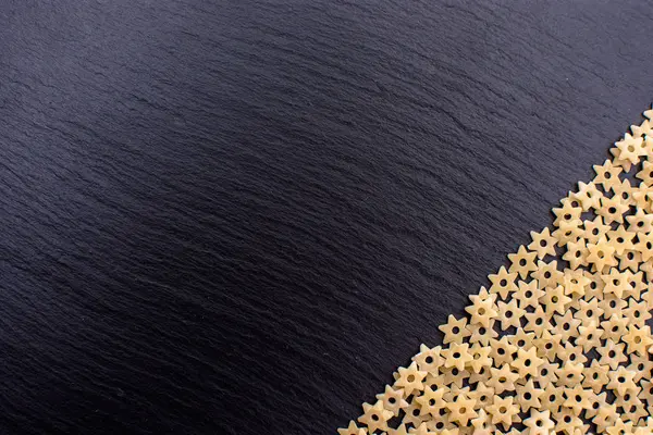 Makarna yıldız şeklinde bir taş yönetim kurulu, metin için yer siyah bir arka plan dayanmaktadır