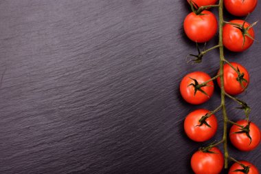 Kırmızı kiraz domates bir siyah taş kayrak kurulu, arka plan yalan