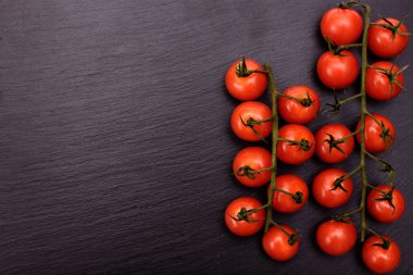 Kırmızı kiraz domates bir siyah taş kayrak kurulu, arka plan yalan