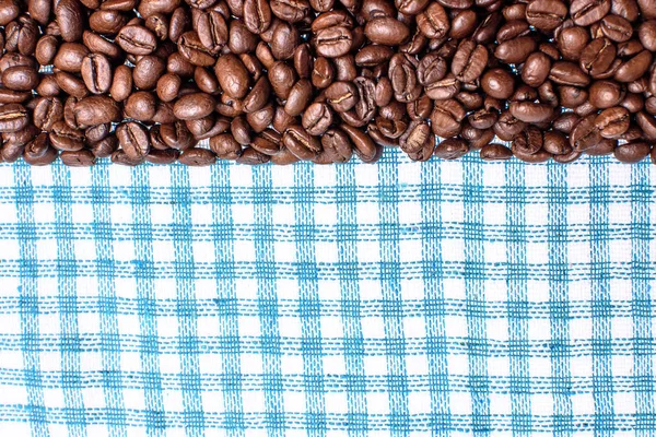 Textura de una toalla de color, una toalla de tipo celular, en la que se encuentra una cierta cantidad de granos de café marrón. Vista superior con un montón de granos de café con espacio para el texto — Foto de Stock