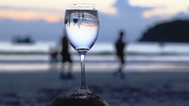 A glass of water put on the beach — Stock Video