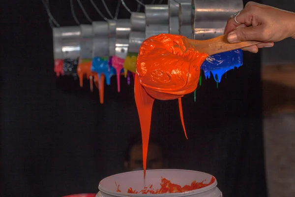 Narancs plasztiszol tinta a fakanállal a gyári póló — Stock Fotó