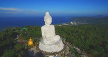 Phuket Big Buddha heykeli dağın tepesinde arkasında sahne mavi gökyüzü ve mavi okyanus vardır.