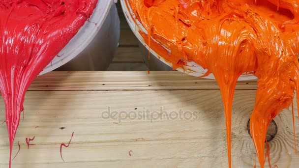プラスチゾル インクの青黄色オレンジと赤の色は バレルから流れました プラスチゾル インクは シャツと任意のファブリックに印刷のために特別です シャツ工場服飾業界で役に立つのインク — ストック動画