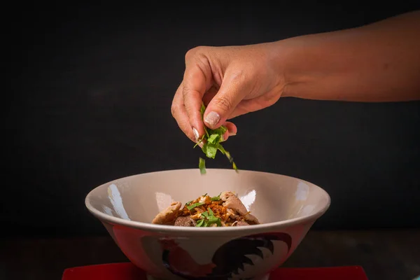 Hand uses chopsticks to pickup tasty noodles on black background