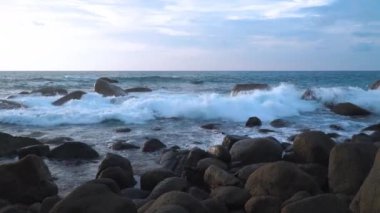 Laem Sai Burnu 'ndaki büyük kayaların üzerinde yavaş çekim video günbatımı. Laem Sai, Kata plajı ile Karon plajı arasında Pu adasına yakın bir yerde çok güzel kayalar ve mercan resifleri var.