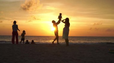 Phuket, Tayland-Ekim 19,2019: Anne ve baba, altın gün batımında, Kata sahilinde, Phuket Tayland 'da deniz feneri geçmişi olan bir çocuk taşıyor.