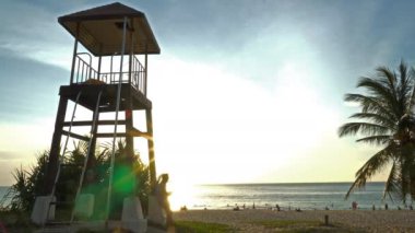 Gün batımında Karon Sahili Phuket 'te yürüyen ve fotoğraf çeken bir adam. Karon sahilindeki cankurtaran kulesinde gün batımı. 