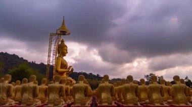 Küçük Buda heykelleri içinde duran altın büyük Buda heykeli Makha Bucha Budist Anıt Parkı 'ndaki birçok küçük Buda heykeli arasında yer alıyor. Nakornnayok Tayland' da..