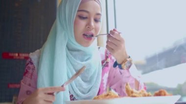 Tayland 'ın Bangkok şehrinin yanındaki restoranda kızarmış tavuk yiyen İslami kadın.