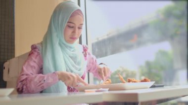 Tayland 'ın Bangkok şehrinin yanındaki restoranda kızarmış tavuk yiyen İslami kadın.