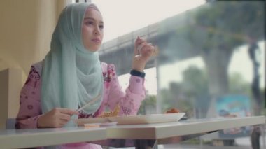 Tayland 'ın Bangkok şehrinin yanındaki restoranda kızarmış tavuk yiyen İslami kadın.