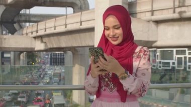 Bts gökyüzünün altındaki üst geçitte cep telefonunu kullanan sevimli İslami bayan.