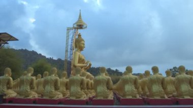 Nakornnayouk, Tayland 'daki Nakornnayouk' taki MAKHA BUDDHIST MEMORIAL PARK adlı kırsal kamu tapınağındaki küçük Buda heykelleri arasında büyük altın bir Buda heykeli.