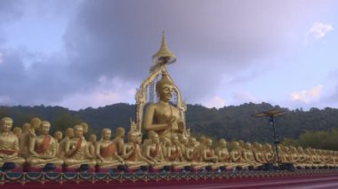 Nakornnayouk, Tayland 'daki Nakornnayouk' taki MAKHA BUDDHIST MEMORIAL PARK adlı kırsal kamu tapınağındaki küçük Buda heykelleri arasında büyük altın bir Buda heykeli.