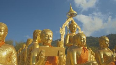 Nakornnayouk, Tayland 'daki Nakornnayouk' taki MAKHA BUDDHIST MEMORIAL PARK adlı kırsal kamu tapınağındaki küçük Buda heykelleri arasında büyük altın bir Buda heykeli.