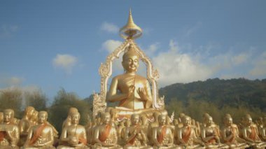Nakornnayouk, Tayland 'daki Nakornnayouk' taki MAKHA BUDDHIST MEMORIAL PARK adlı kırsal kamu tapınağındaki küçük Buda heykelleri arasında büyük altın bir Buda heykeli.